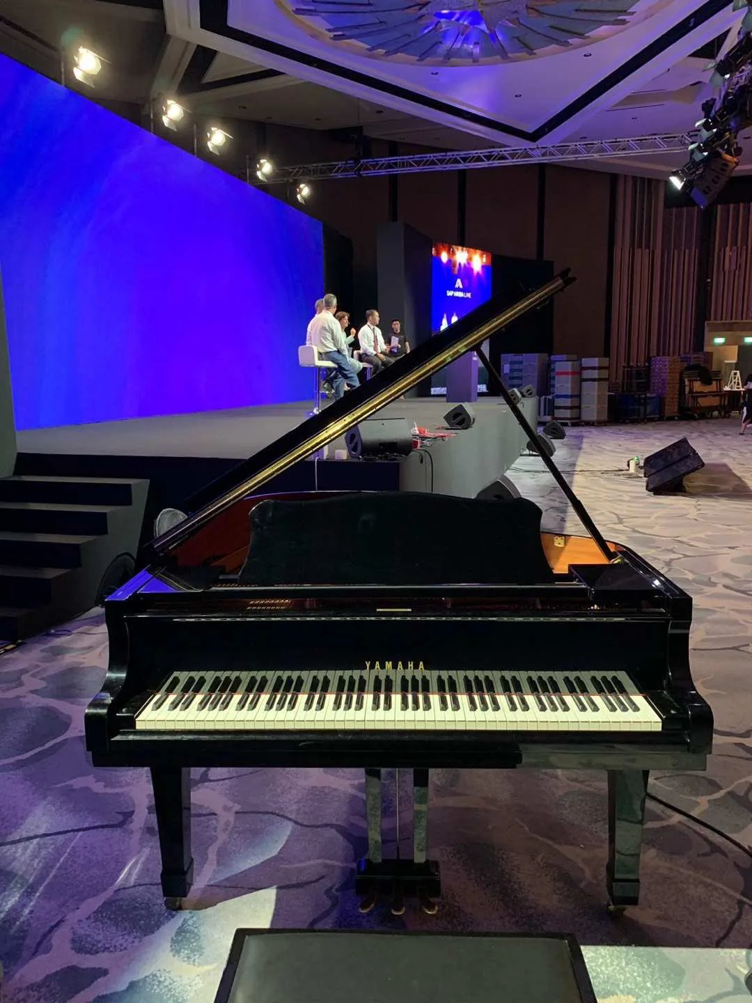 A grand piano on a blue lit event stage