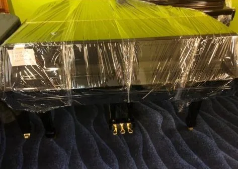 A grand piano wrapped and strapped for transport