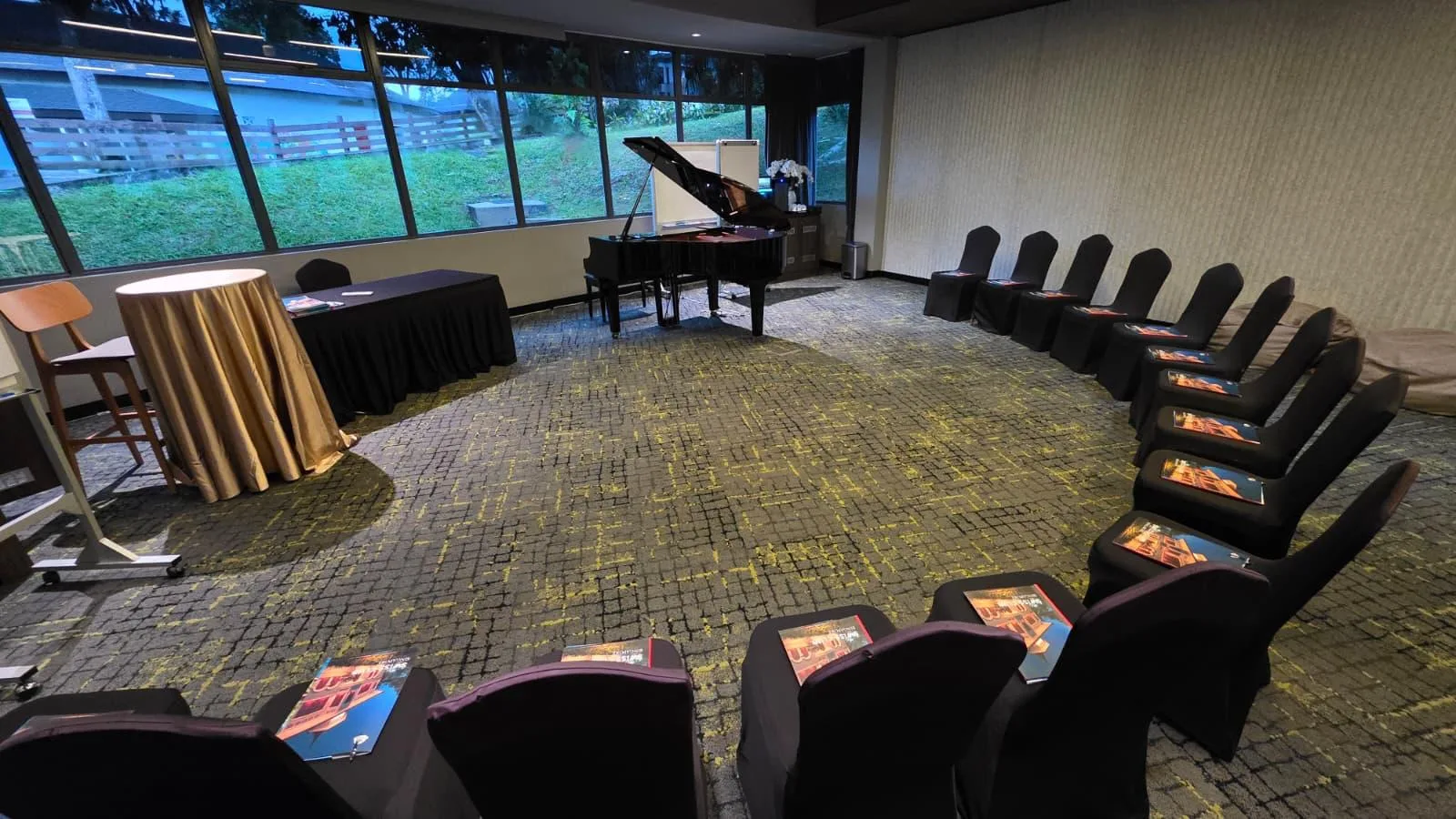 A function room laid out with chairs in a curve and a grand piano by the windows