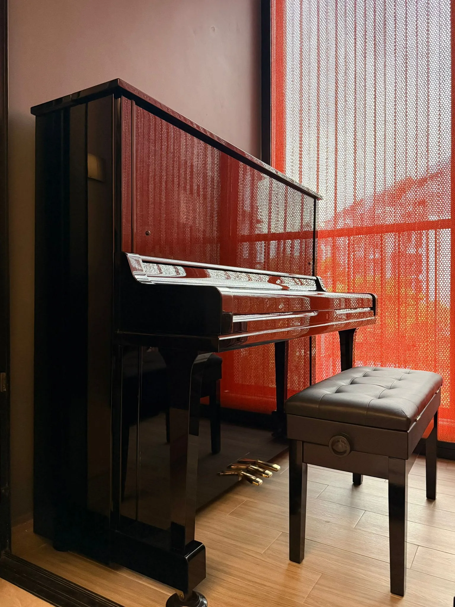 An upright piano beside a red screen in a home
