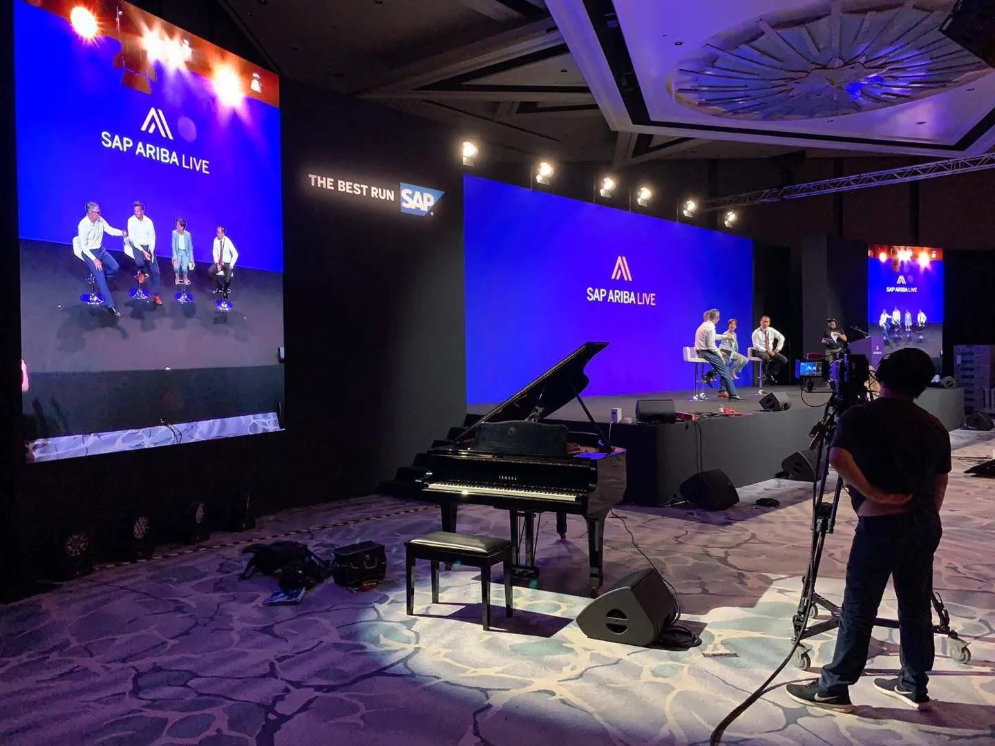 A grand piano beside a lit conference stage