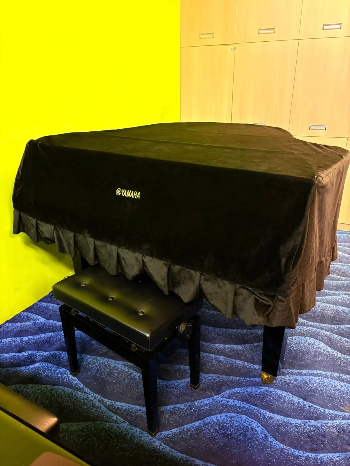 A Yamaha grand piano under its cover in the viewing gallery