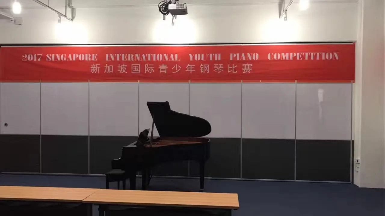 A grand piano in a practice hall beneath a piano competition banner
