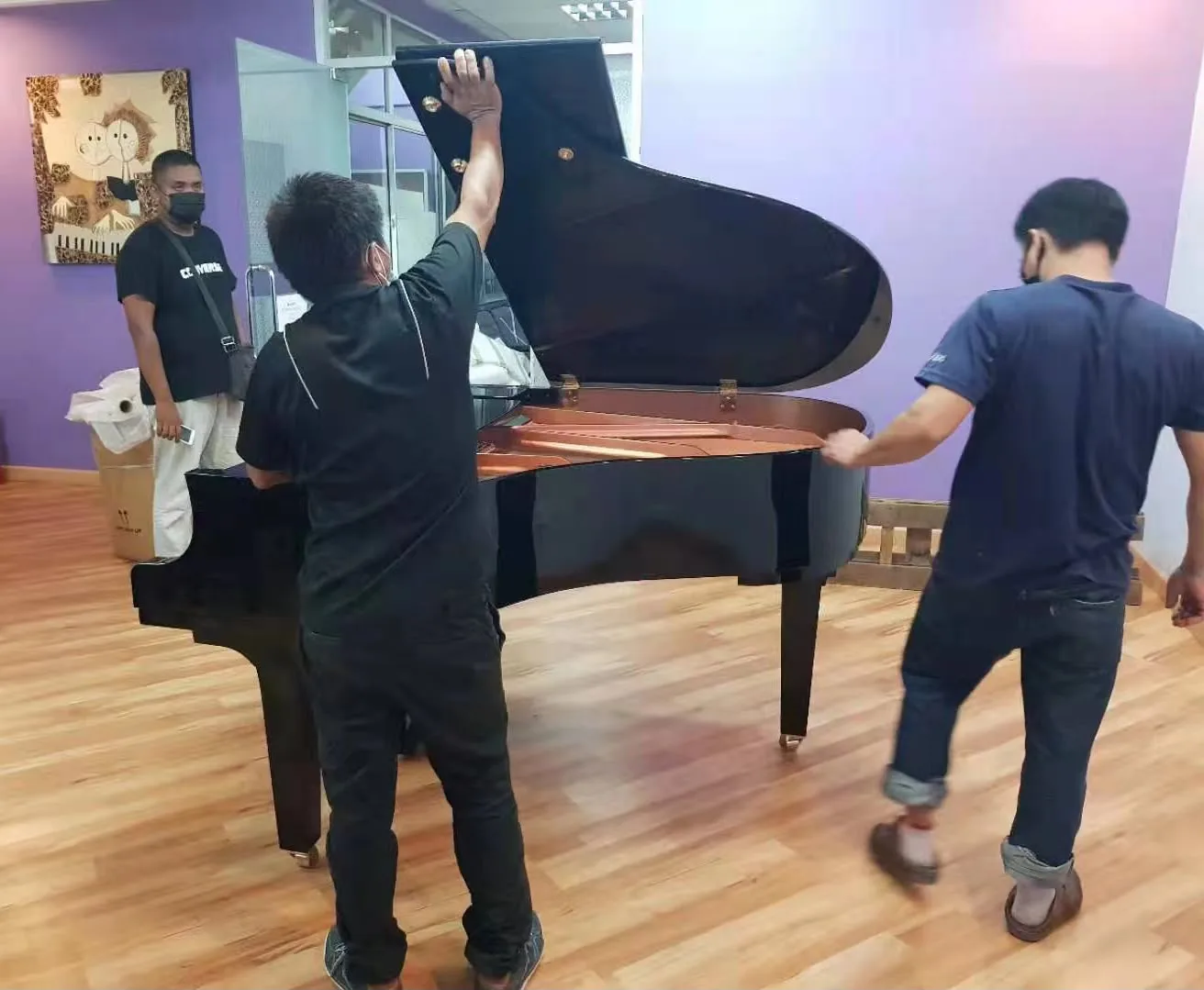 Movers lifting the lid back onto a grand piano