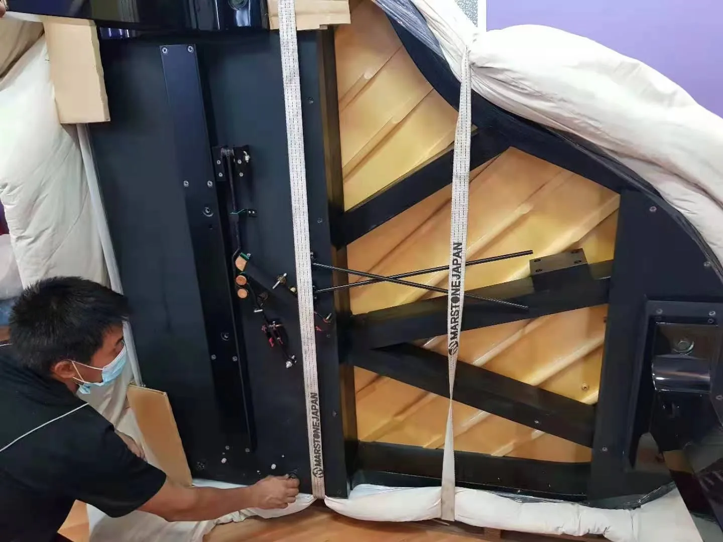 The underside of a grand piano strapped to a padded skid