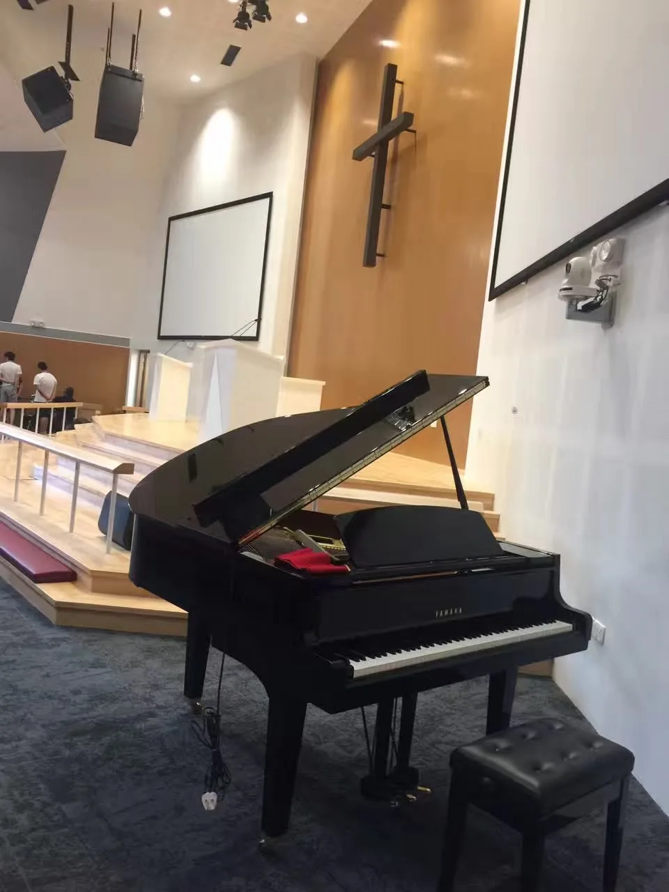 A Yamaha grand piano set up at the foot of a hall stage