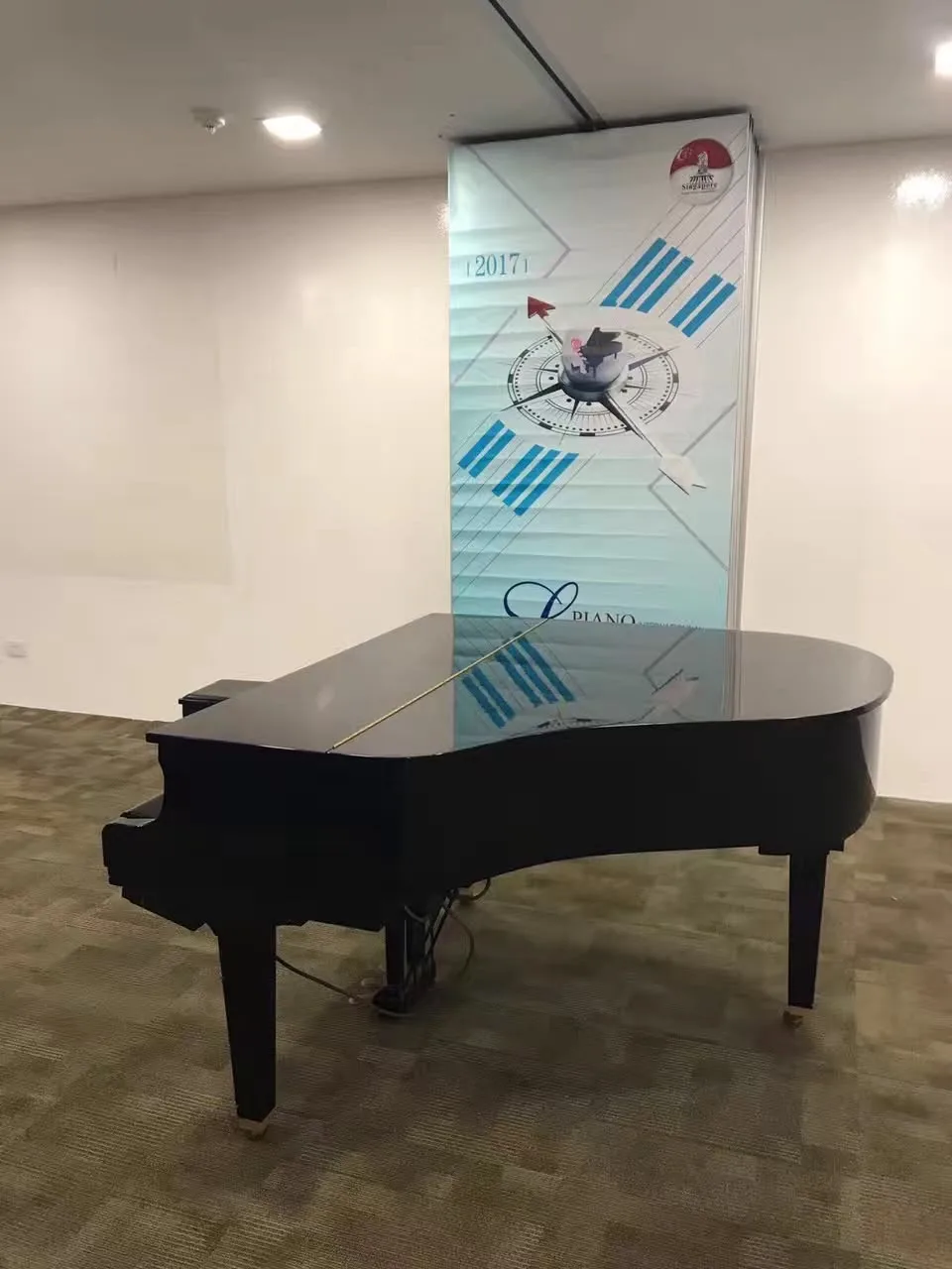 A grand piano standing in a corporate lobby beside an event banner