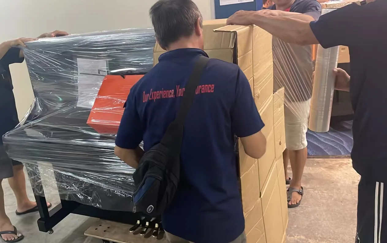 An upright piano being wrapped in film before a move