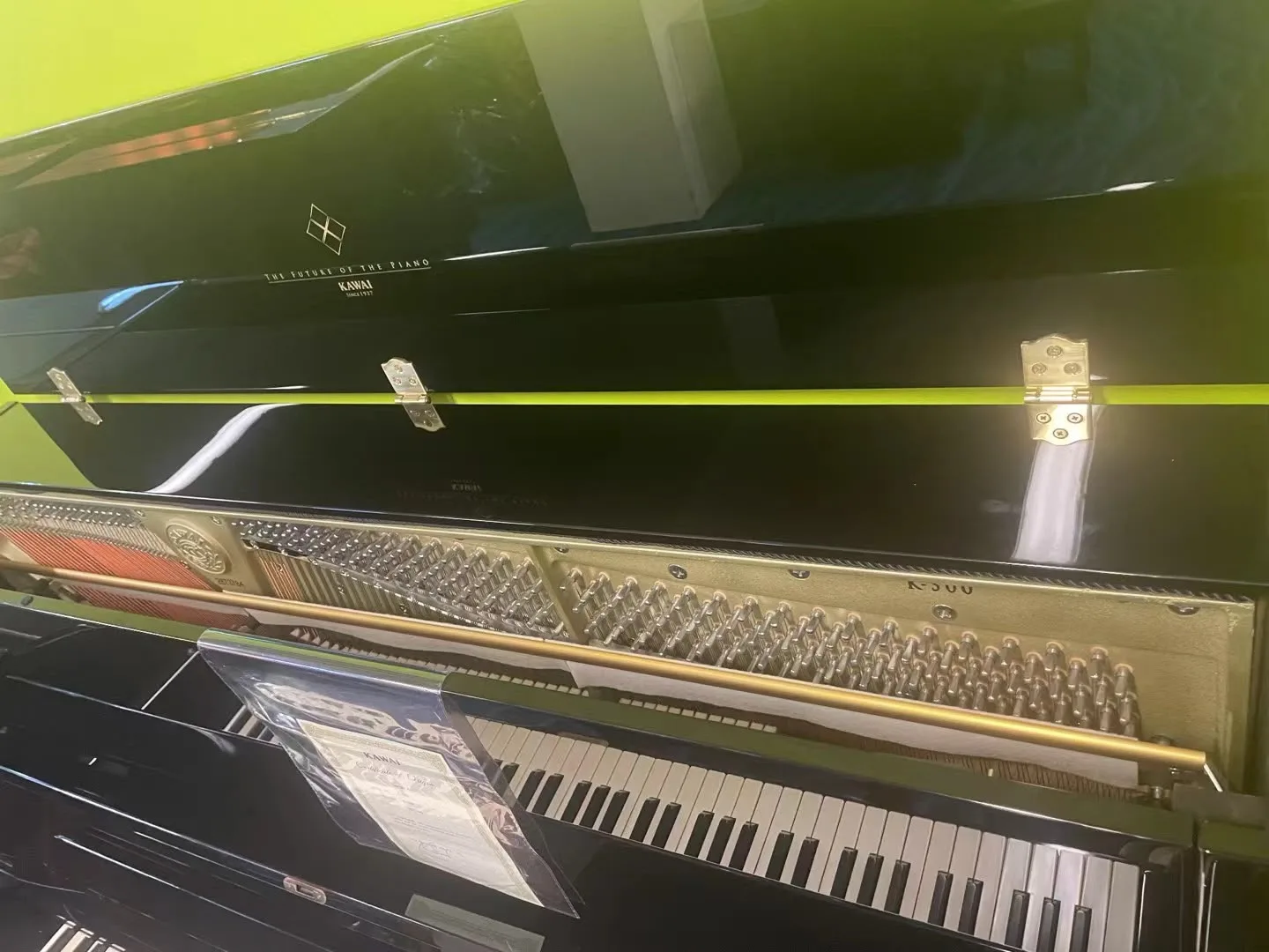 The lid and plate of a Kawai grand piano reflected in its polished case