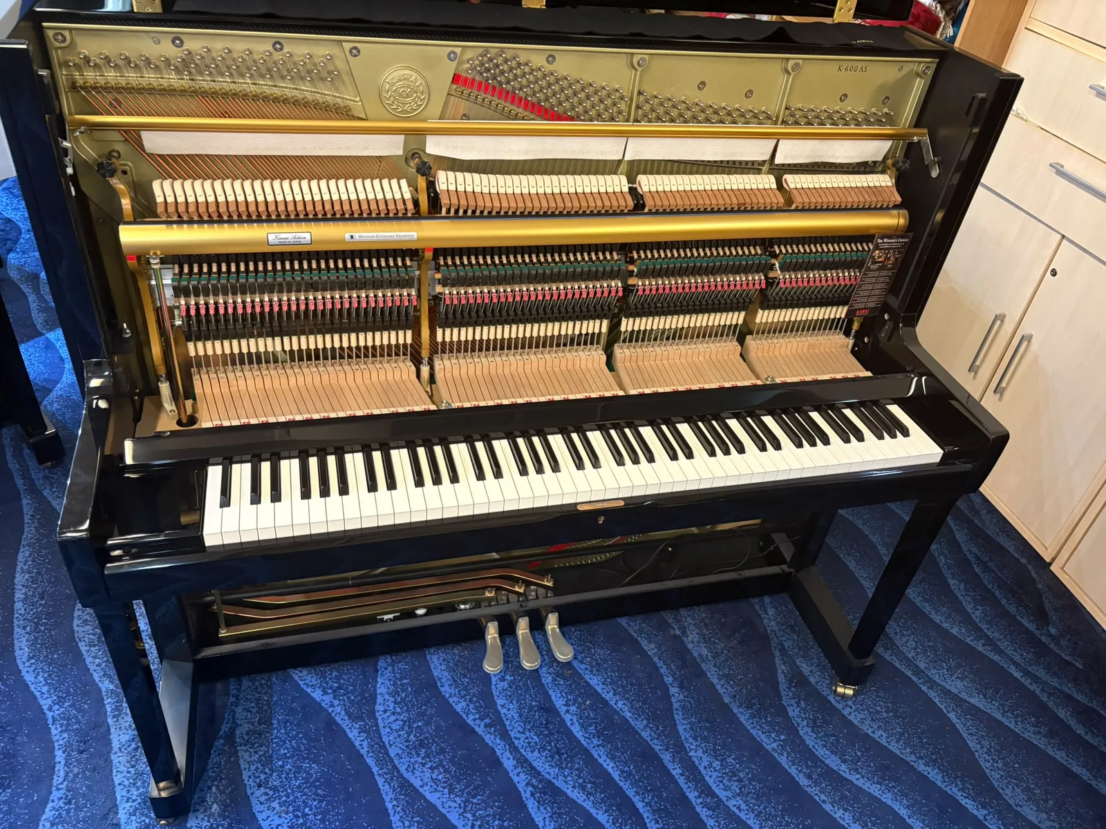 A Kawai upright piano seen from the treble end with the action exposed