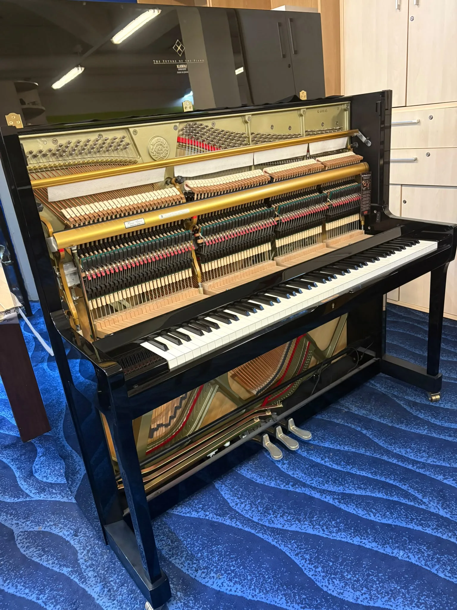 A Kawai K-600AS upright piano with the top board off on the viewing gallery floor