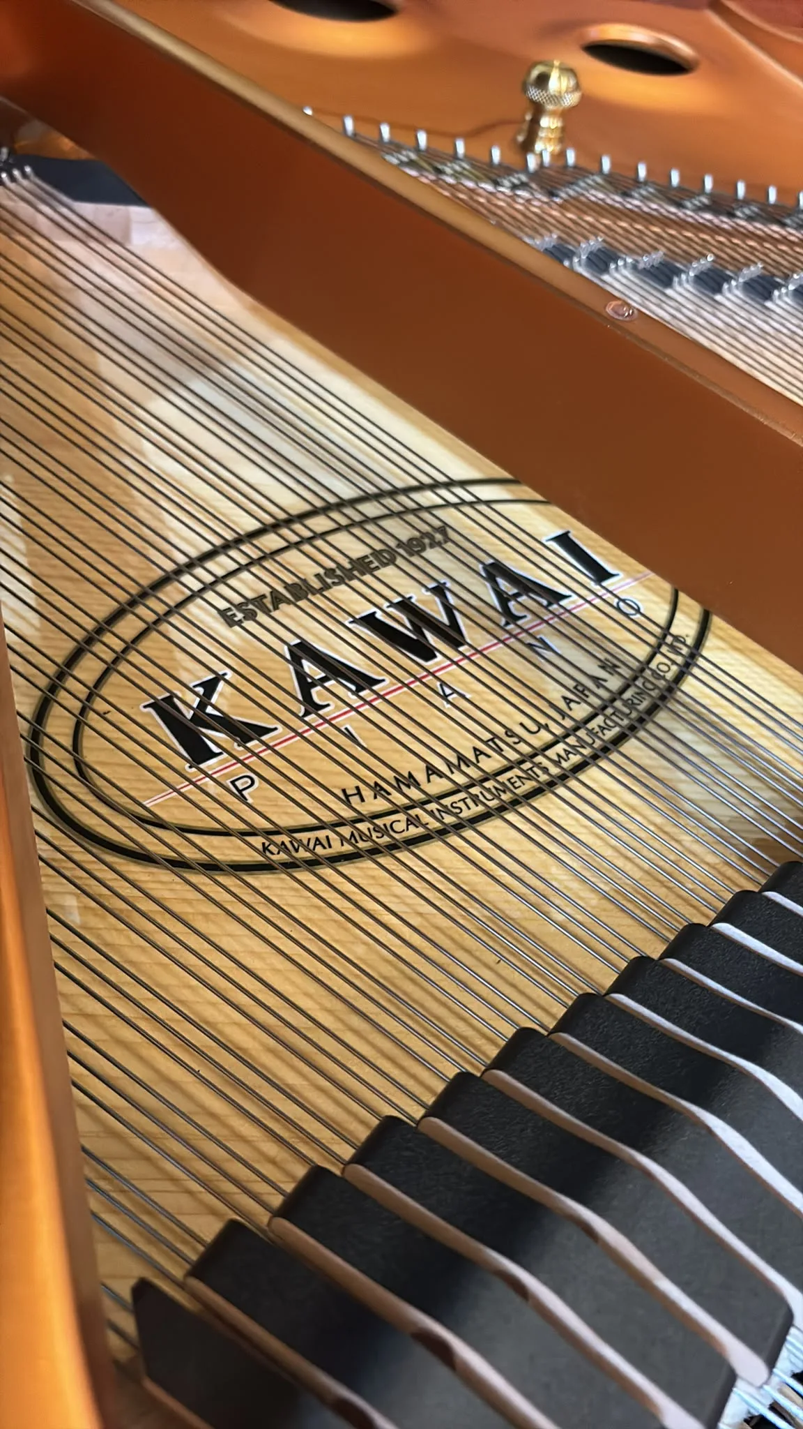 The Kawai roundel cast into the plate of a GX-1 grand piano