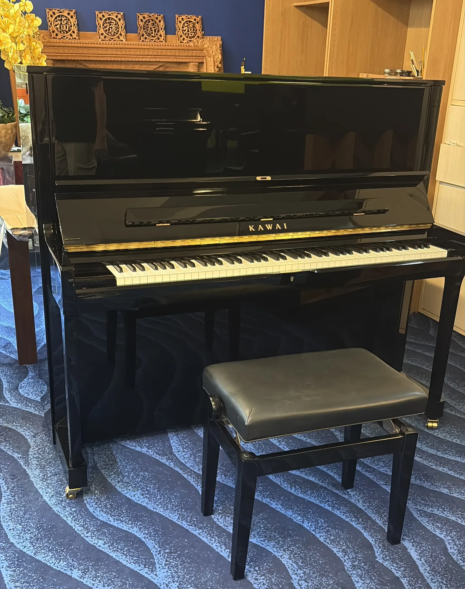 A Kawai upright piano with its bench on the floor at IMM