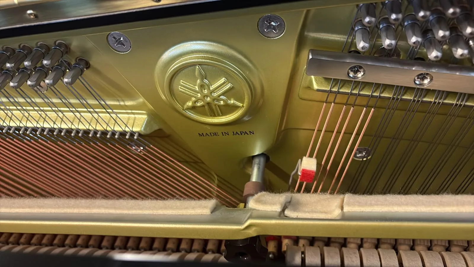 The Yamaha mark and made in Japan cast into the plate of an upright piano