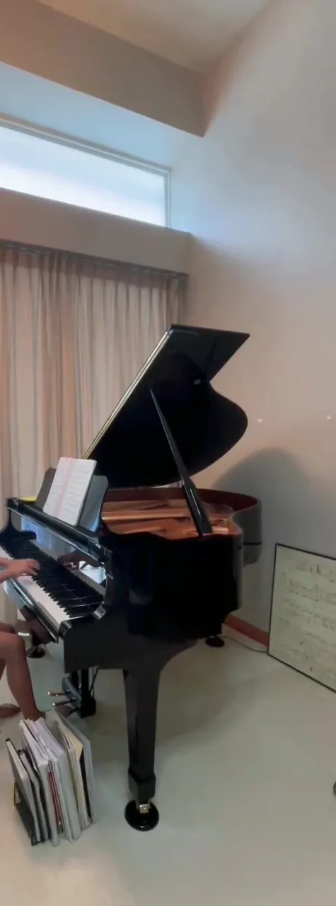 A grand piano in a home beside a window